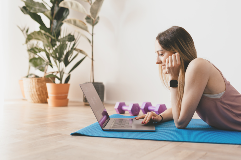 Vrouw op yoga mat achter haar laptop